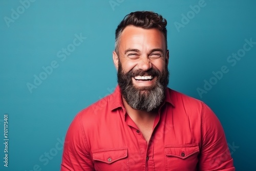 Portrait of a handsome man with beard and mustache laughing over blue background