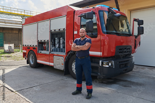 Confident firefighter stands with crossed arms  exuding resilience and preparedness  ready to respond to emergencies alongside a modern fire truck  showcasing the heroism and strength of the fire