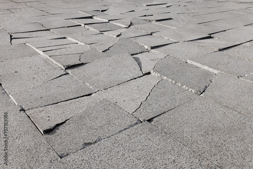 Cracked granite sidewalk tiles. Selective focus.