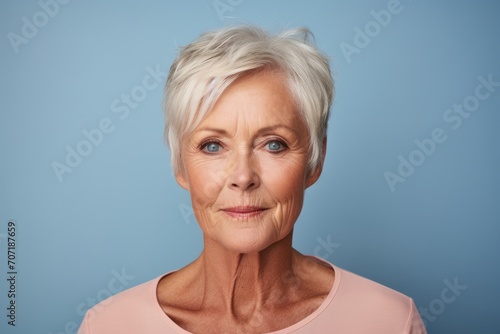 Thoughtful mature woman. Portrait of senior woman looking at camera and smiling while standing against blue background