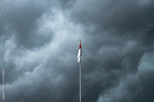 Dramatic, dark, blue red and white indonesian flag with dark couldy sky on the backgroundRain And Thunderstorm In Dramatic Sky photo