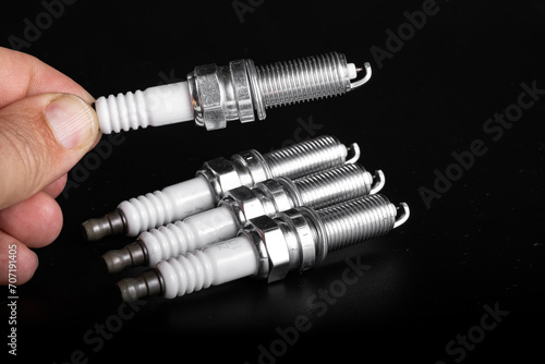 A new candle in a man's hand on a white background. The concept of choosing spark plugs.