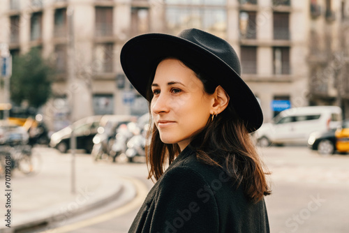 Chill young woman wearing black hat is walking through an european city. Outdoors portrait.