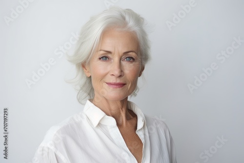 Portrait of beautiful senior woman looking at camera on grey background.