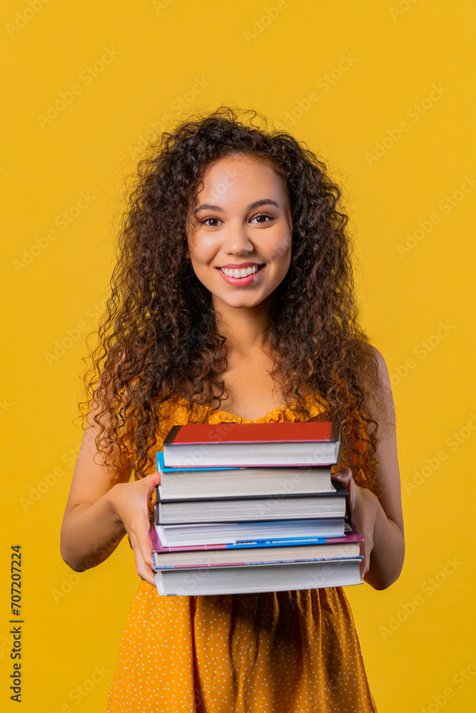 Smiling adult student woman with stack of books from library, yellow background Smiling adult student woman with stack of books from library, yellow background