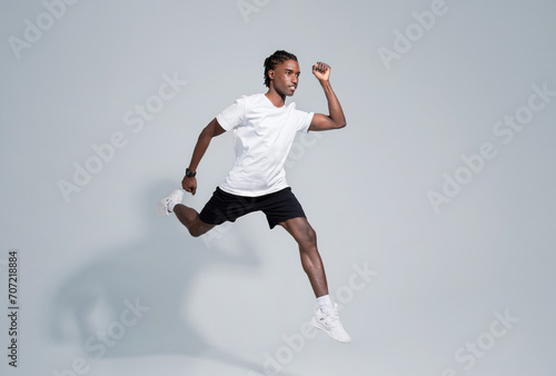 Dynamic black man in sportswear running on grey studio background