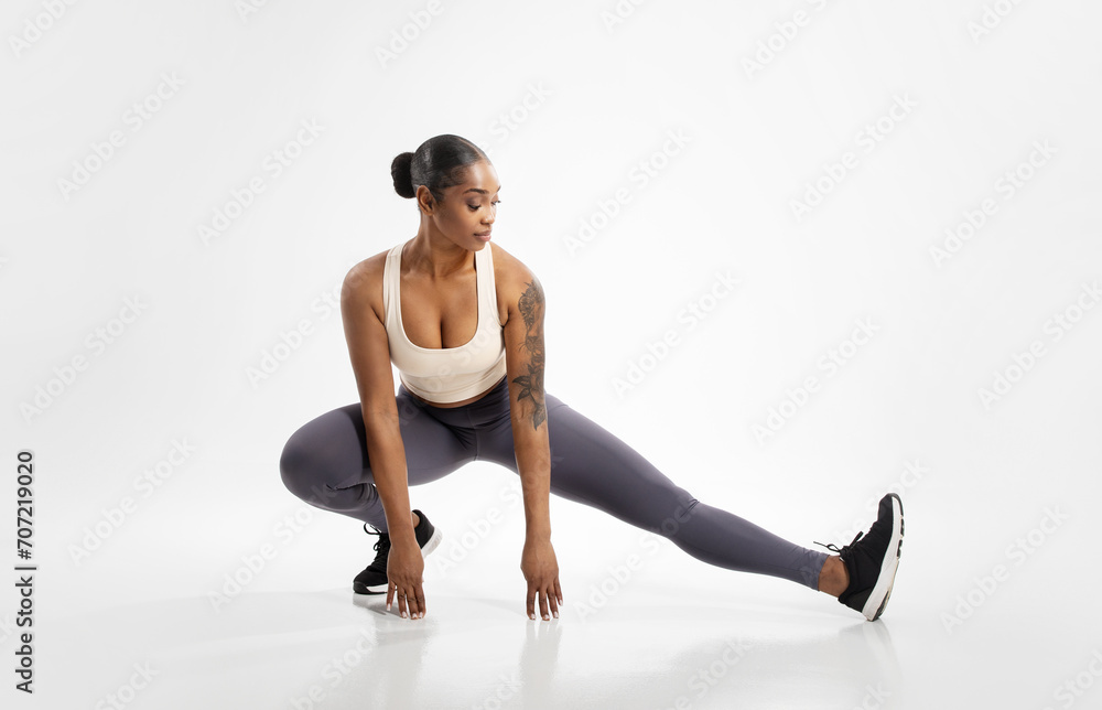black lady making extended leg squat pose stretching legs, studio black lady making extended leg squat pose stretching legs, studio