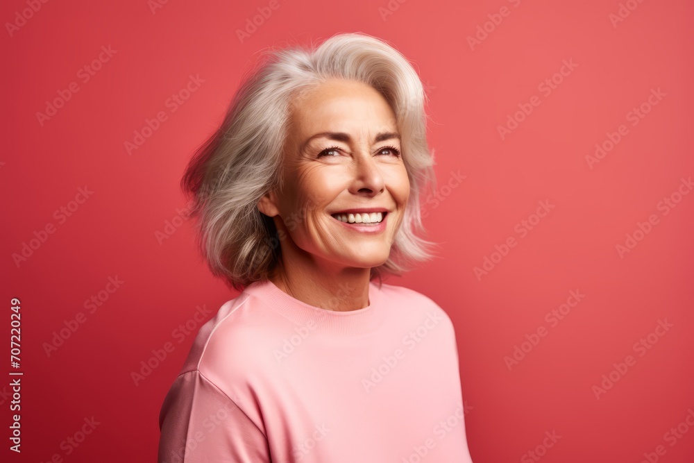 Portrait of a smiling senior woman posing isolated over red background. Portrait of a smiling senior woman posing isolated over red background.
