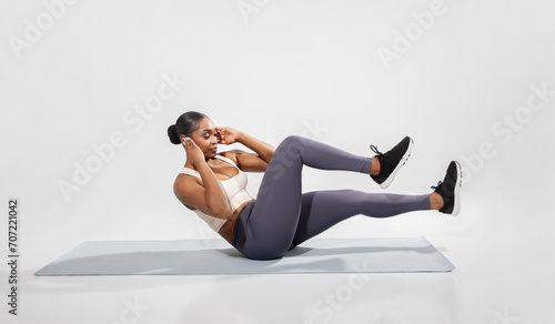 Fit black woman in sportswear doing abdominal bicycle exercise, studio photo
