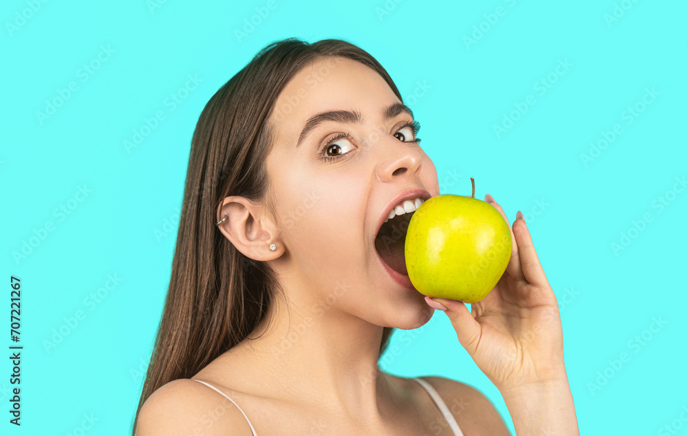 Eating apple. Portrait of woman eating green apple. Smiling woman with healthy teeth holding green apples. Healthy diet food. Stomatology. Woman with perfect smile holding apple, blue background Eating apple. Portrait of woman eating green apple. Smiling woman with healthy teeth holding green apples. Healthy diet food. Stomatology. Woman with perfect smile holding apple, blue background