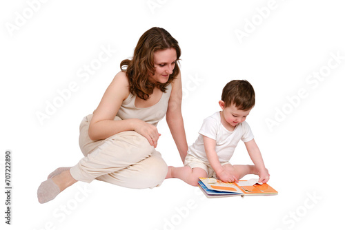 Happy baby with mother reading a book on studio, isolated on white background. Portrait of a smiling child with mom, isolated on white background. Kid about two years old (one year nine months)