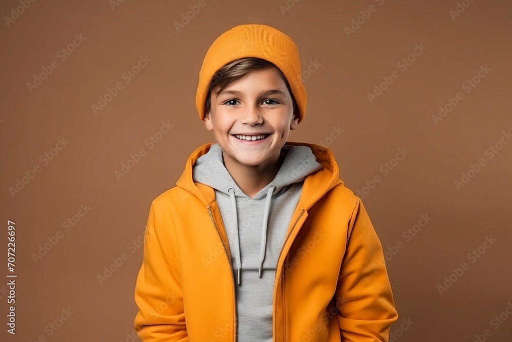 Portrait of a happy boy in a yellow jacket and hat on a brown background Portrait of a happy boy in a yellow jacket and hat on a brown background