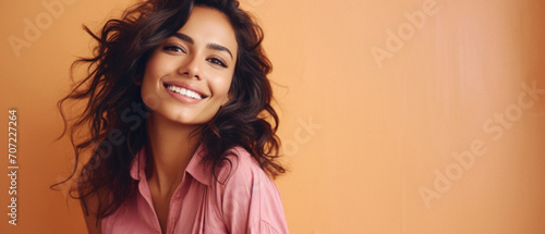 Beautiful smiling woman in pink shirt looking at camera isolated on orange