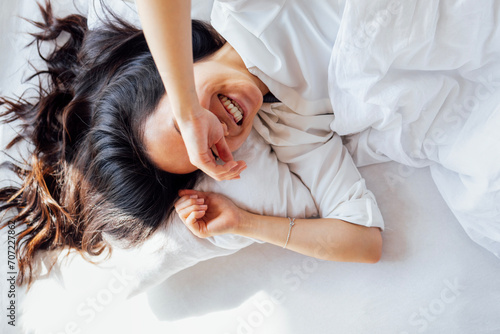 Photography Attractive happy Asian woman lies on a white linen bed in the morning
