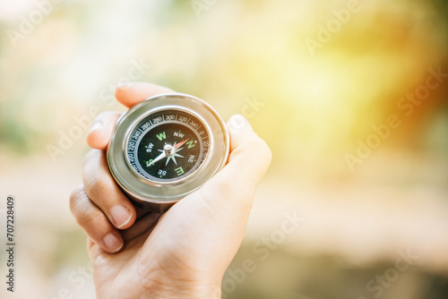 Traveler holds a compass in a park finding her way through the confusion. In her hand the compass represents guidance exploration and the journey to overcome defeat.