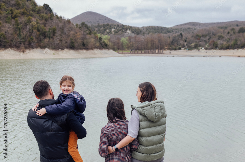 Happy family with two children by lake. People are dressed in warm jackets and coats