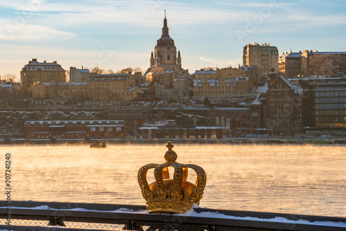 The swedish royal crown symbol, gold colored, infront of Stockholm skyline in winter, with the old Church of Katarina in the background. photo