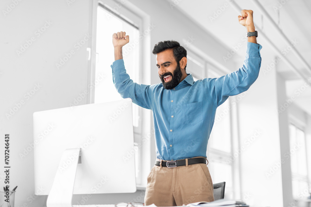 Exuberant indian businessman celebrating success at his computer
