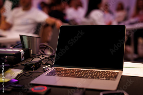 A presenter using a laptop in a conference room with a large audience