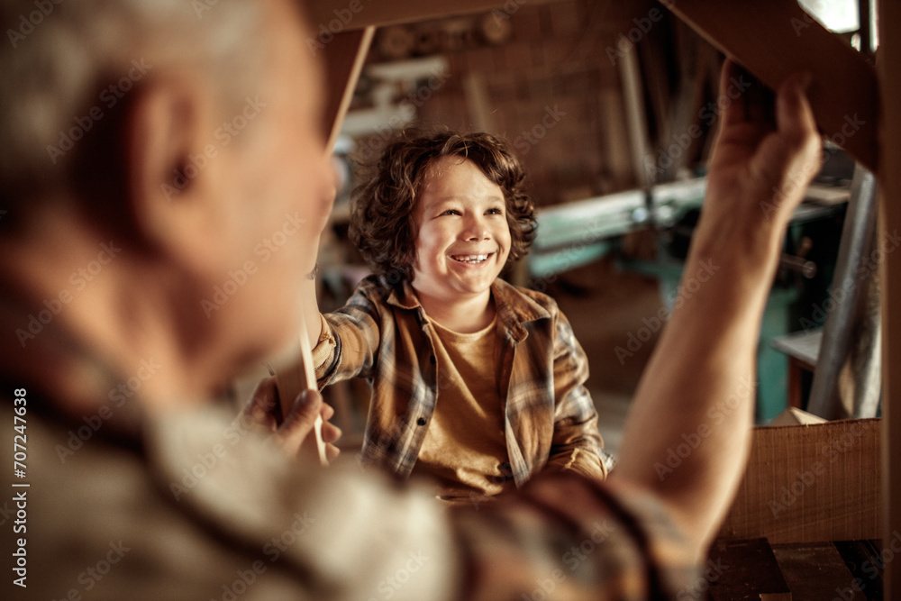 Senior man teaching grandson woodworking in workshop Senior man teaching grandson woodworking in workshop