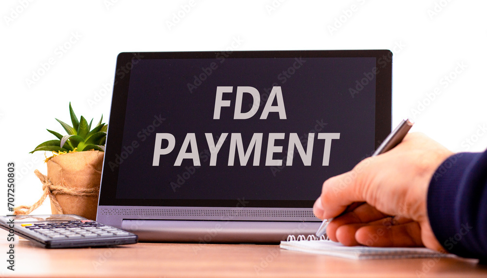 FDA Food and Drug Administration payment symbol. Concept words FDA payment on beautiful black tablet. Beautiful white background. Calculator. Businessman hand. Business FDA payment concept. Copy space FDA Food and Drug Administration payment symbol. Concept words FDA payment on beautiful black tablet. Beautiful white background. Calculator. Businessman hand. Business FDA payment concept. Copy space