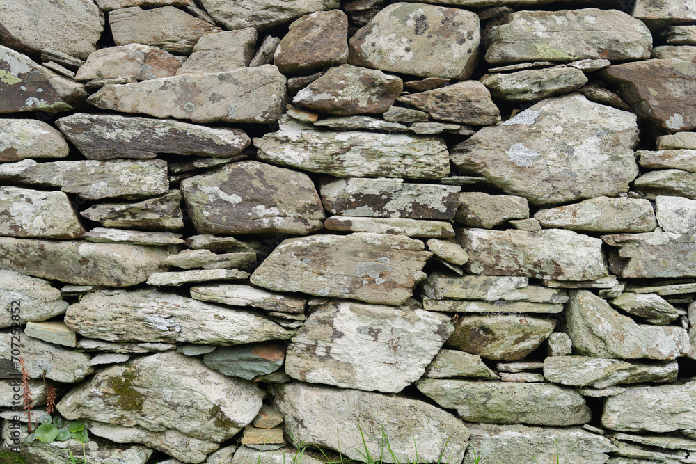 Beautiful close up of a light gray dry stone wall with the remains of time marked on the surface and texture in a rural area ideal for wall paper