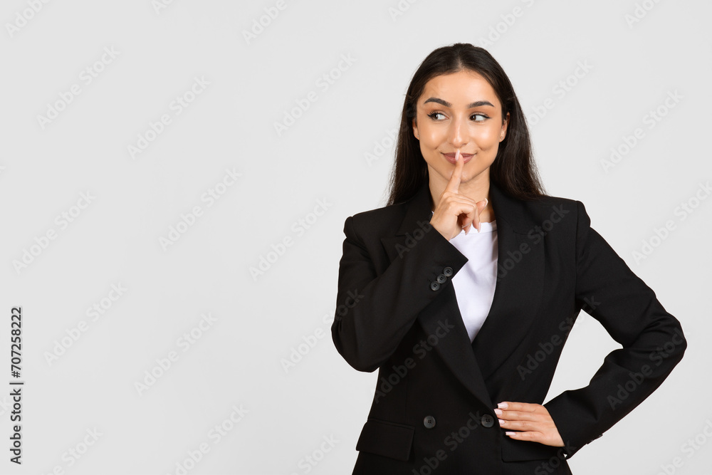 Businesswoman with finger on lips signaling silence Businesswoman with finger on lips signaling silence