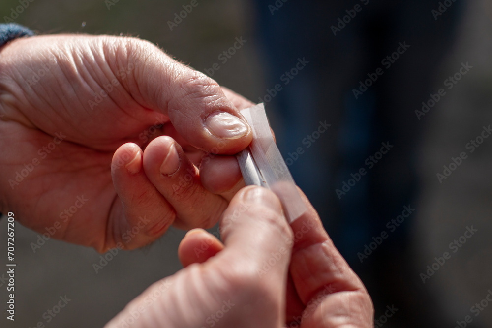 Man's hands rolling a cigarette, the paper on the tobacco