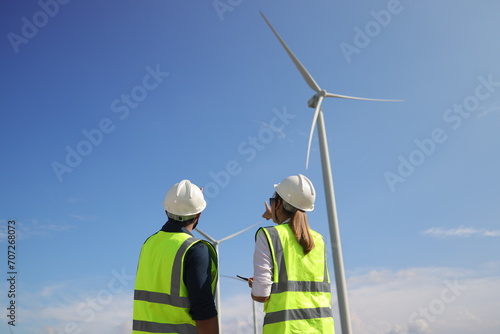 A couple of Electric engineers working together at a wind turbine farm.