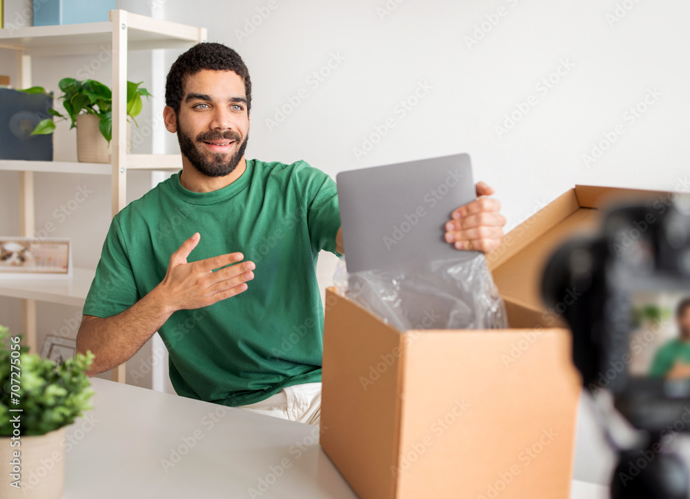 Long stock description: Smiling man in green shirt excitedly unboxing a new silver laptop Long stock description: Smiling man in green shirt excitedly unboxing a new silver laptop