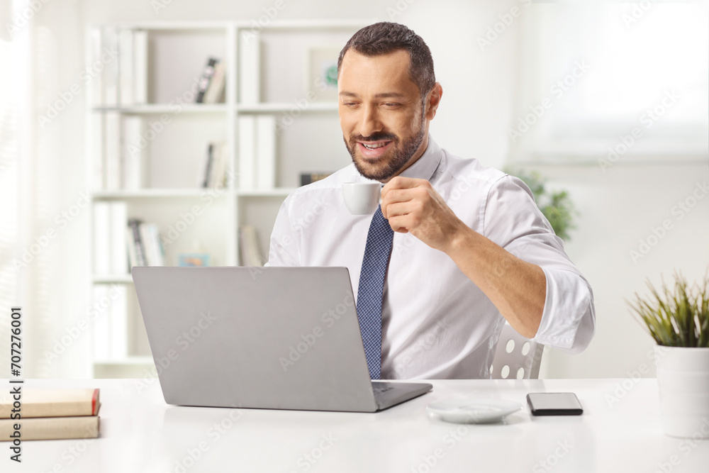 Man drinking coffee and working at a laptop computer Man drinking coffee and working at a laptop computer