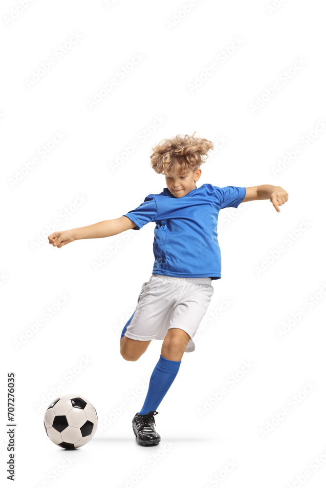 Boy in a football kit kicking a ball