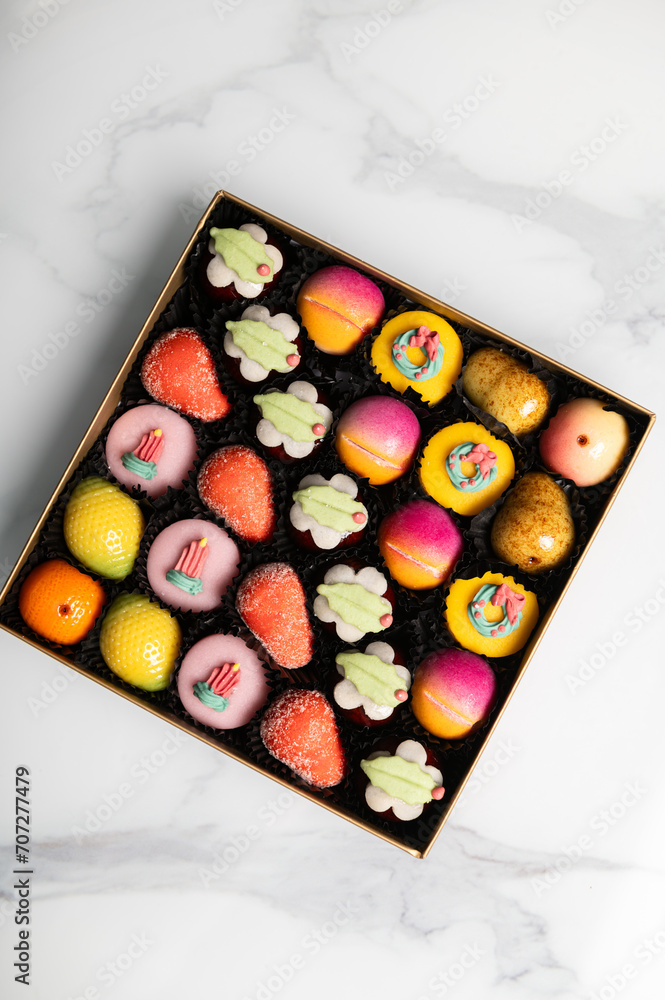 Box of rainbow marzipan sweets in form of different fruits and cakes Box of rainbow marzipan sweets in form of different fruits and cakes