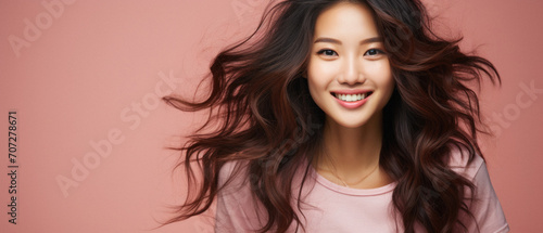 Smiling young asian woman with long hair isolated on pink background