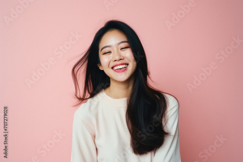 Portrait of beautiful young asian woman smiling on pink background .