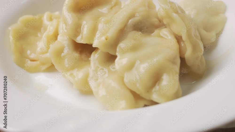 Transfer dumplings from the pan to a white plate with a slotted spoon. Medium plan Transfer dumplings from the pan to a white plate with a slotted spoon. Medium plan