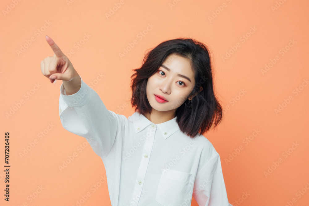 Portrait of beautiful young asian woman pointing finger on orange background Portrait of beautiful young asian woman pointing finger on orange background
