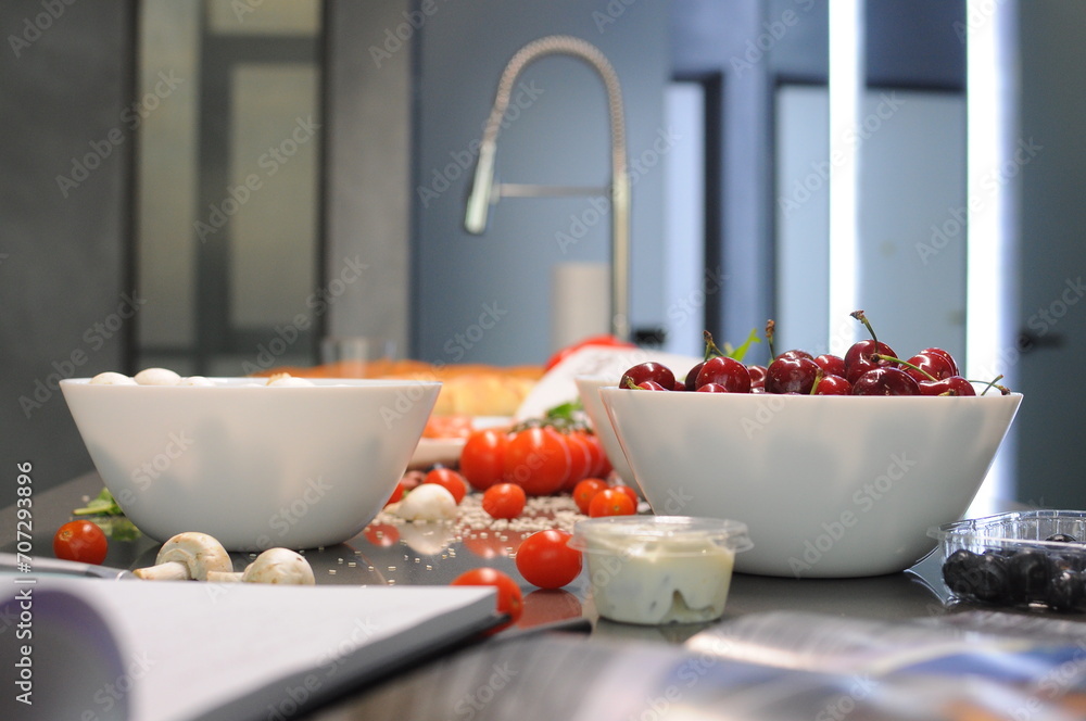 cherries in a plate, tomatoes, mushrooms, sauces on the table in the kitchen cherries in a plate, tomatoes, mushrooms, sauces on the table in the kitchen