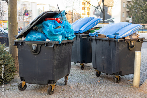 Überquellende Müllcontainer mit Abfall und Müllsäcken stehen auf dem Gehweg und warten auf die Abholung durch die Müllabfuhr