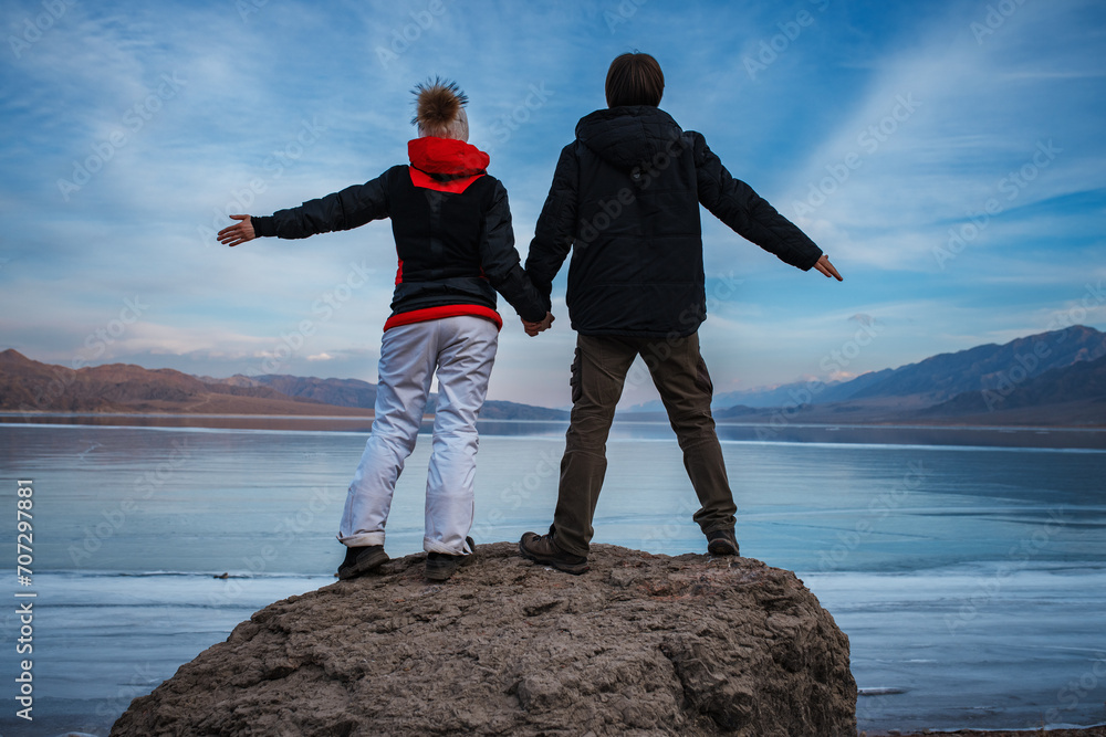 Fototapeta premium Man and woman holding hands on frozen lake background in winter