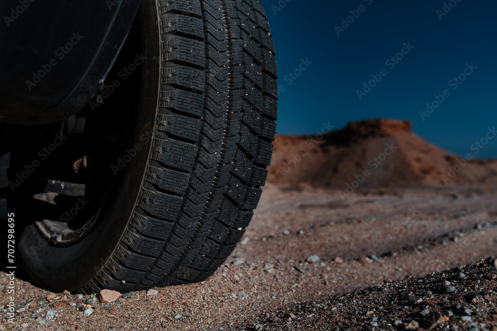 Car wheel on sand in the mountains close-up view
