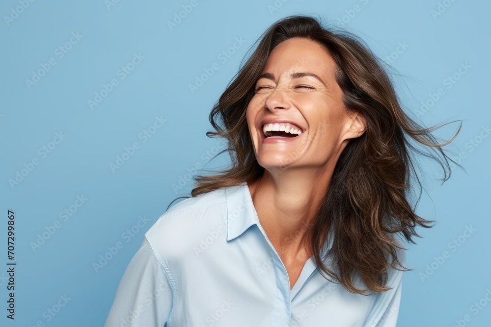 Portrait of happy woman laughing and looking up with closed eyes over blue background Portrait of happy woman laughing and looking up with closed eyes over blue background