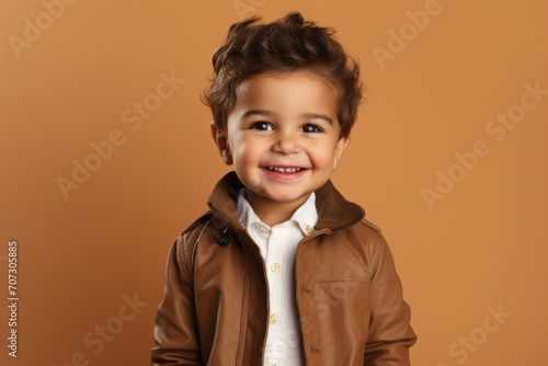 Portrait of a smiling little boy in a brown jacket against a brown background