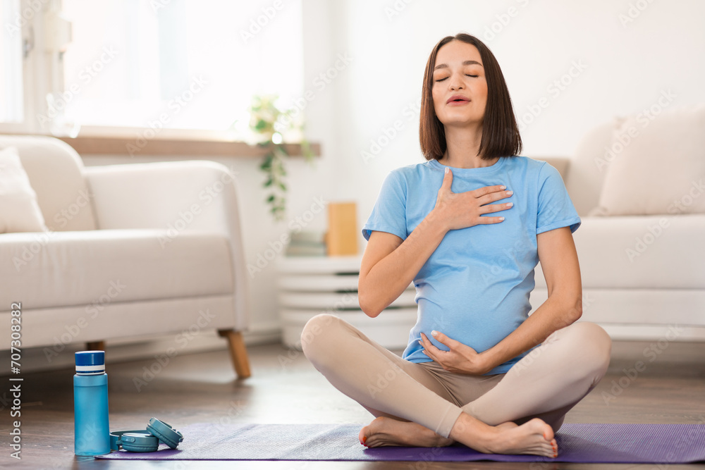 Expectant pregnant woman on yoga mat doing breathing exercises indoor Expectant pregnant woman on yoga mat doing breathing exercises indoor