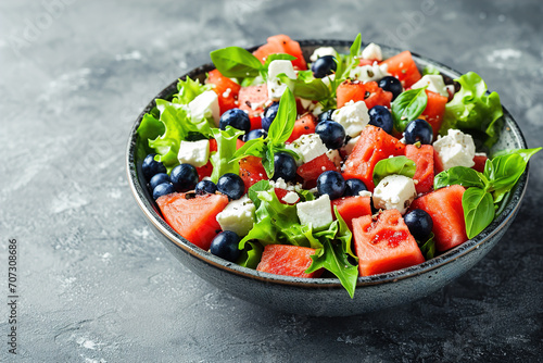 Summer salad with watermelon, blueberries and feta cheese, above view on a dark stone background, Image for booklets, menus
