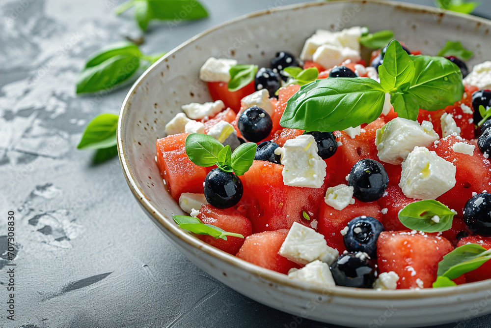 Summer salad with watermelon, blueberries and feta cheese, above view on a dark stone background, Image for booklets, menus