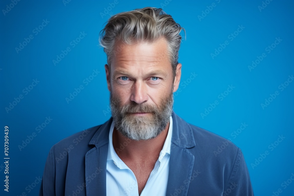 Portrait of handsome mature man with grey beard and mustache. Isolated on blue background. Portrait of handsome mature man with grey beard and mustache. Isolated on blue background.