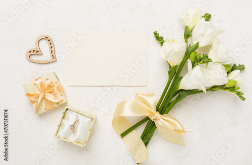 White fresia flower and gift box with diamond ring on concrete background, top view