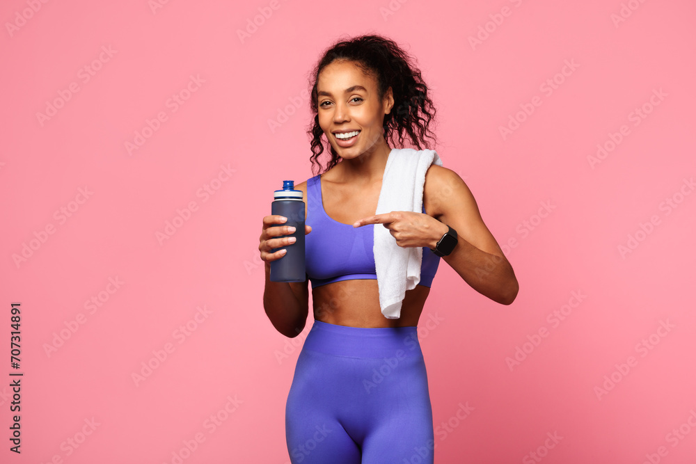 Sporty black lady in activewear holding towel and bottle, studio Sporty black lady in activewear holding towel and bottle, studio
