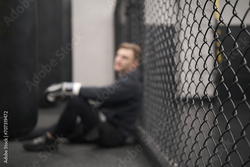 Defocused background, boxer resting, mma or mixed martial arts, sports training at gym photo